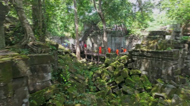 Two tourists explore the ancient ruins of Beng Mealea temple in Cambodia. The temple is known for its unrestored state, allowing visitors to experience its jungle-clad beauty.