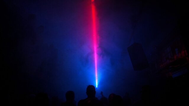 thump. Dark underground club with single colorful laser beam through haze. lifestyle magazines, social media lookbooks, designed for lifestyle magazines and social media content, inspires lifestyle.