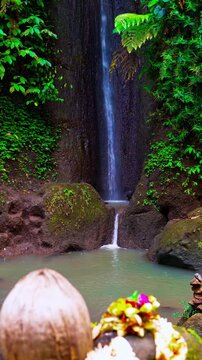 Scenic tropical waterfall cascading in deep jungle canyon with traditional flower offering 4K