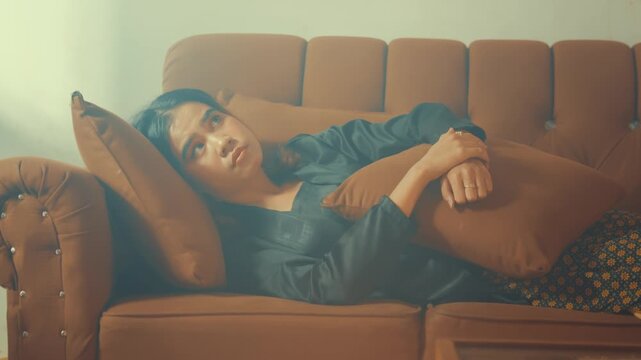 Young Woman Staring Blankly at Ceiling on Couch