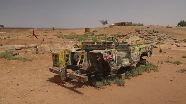 Stripped abandoned rally truck wreck covered in graffiti and stickers standing as desert landmark in southern Moroccan outpost