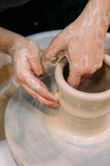 Fototapeta premium Ceramics inspiration. Creative potter. Unrecognizable specialist woman hands working with artisan pot using wheel in workplace.