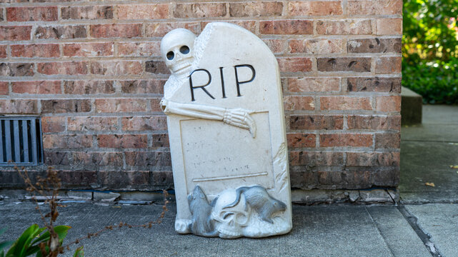 Plastic Halloween Tombstone with Skeleton on Brick and Concrete Background