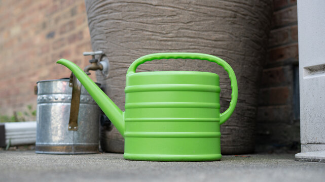 Bright Light Green Plastic Gardening Watering Can on Rustic Background Level Shot
