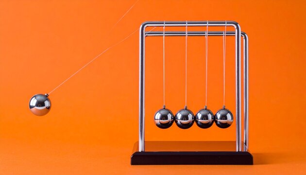 Newton&rsquo;s cradle with spheres against bright orange background
