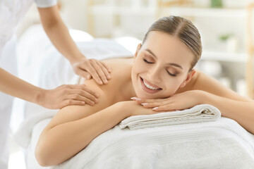 Obraz premium Massage therapist touching back and shoulder of happy woman at spa treatment session. Hands massaging skin of lying girl for relaxation and stress relief, relaxing therapeutic body care procedure