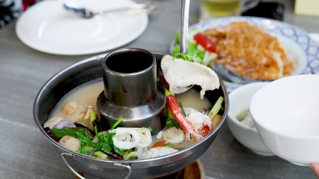 Serving Spicy Thai Tom Yum Seafood Soup From Hot Pot