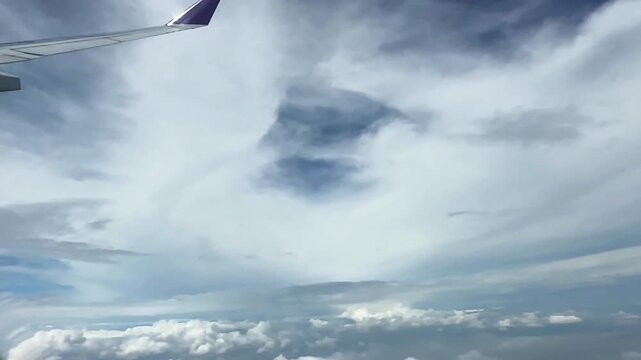Clouded blue sky through aircraft window high altitude flying passing by