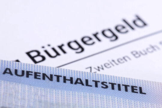 Antrag auf B&uuml;rgergeld und Dokument Aufenthaltstitel als Symbol f&uuml;r die Zahlungen von Sozialleistungen an ausl&auml;ndische B&uuml;rger in Deutschland