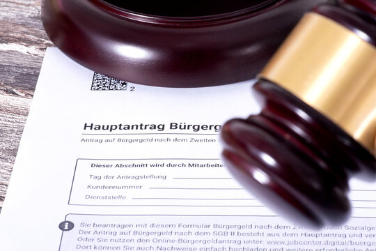 Antrag auf B&uuml;rgergeld und Richterhammer als Symbol f&uuml;r eine Klage gegen das Jobcenter