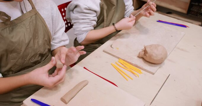 Ceramic workshop. Clay modeling. Two creative children forming molding raw using pottery color tool in professional art workplace.