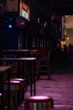 Empty nightlife street with neon lighting, bar tables and atmospheric urban mood at evening in Patong tourist district, Phuket, Thailand dark Asian nightlife and cinematic travel background scene