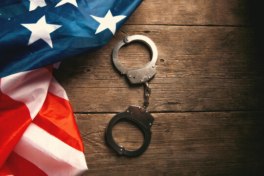 Handcuffs on the background of the American flag on a wooden background