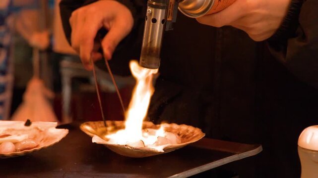 Chef Using Blowtorch to Flame Grill Fresh Scallops in Tokyo Market