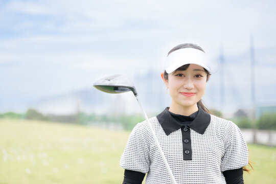 ゴルフ練習場で笑顔のカメラ目線の女性のスポーツライフスタイルイメージ
