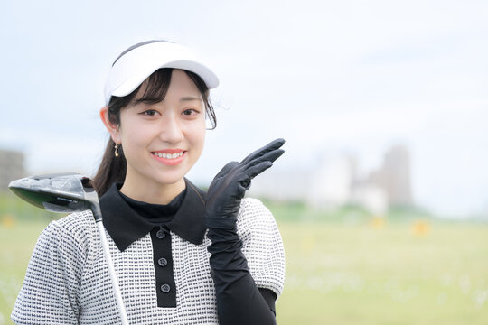 ゴルフ練習場で上達や成功を喜ぶ、オススメや紹介ポーズの女性のスポーツライフスタイルイメージ　カメラ目線の笑顔