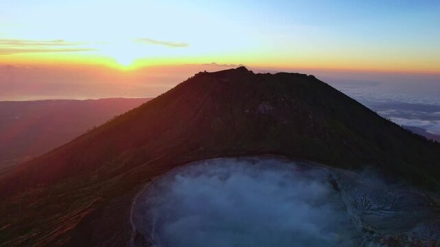 Aerial Shot Capturing Sunrise Casting Warm Colors On Volcanic Crater With Lowhanging Clouds