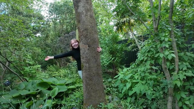 Woman happily hugs tree trunk in a park