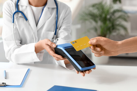 Male hand with credit card and doctor paying via terminal in clinic, closeup