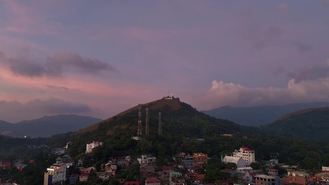 Sunset time lapse over Mount Tapyas and Coron town in Palawan Philippines with tropical hills evening clouds pink sky and distant mountain silhouettes