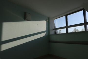 Fototapeta premium Sunlight slices across pale blue walls