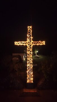 Illuminated large cross landmark on Mount Tapyas in Coron Palawan Philippines seen in low light with dark sky surrounding trees and quiet hilltop setting