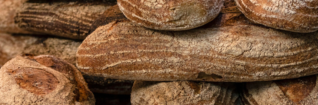 Panorama of loaves of large white sourdough bread on a bakers stall food market