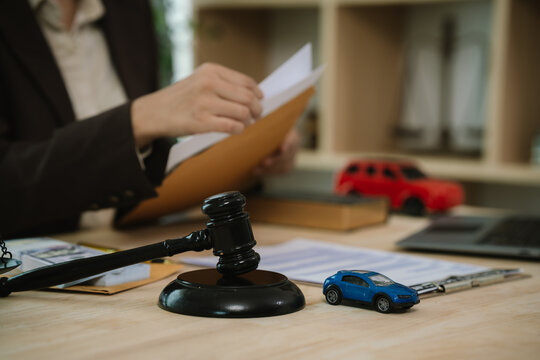 Professional reviewing a contract agreement beside cash and a model car, representing auto insurance, financial transactions, legal services, and vehicle financing.