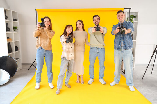 Happy photographers with cameras and model during master class in studio