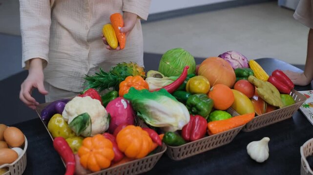 Children playing with a colorful set of toy vegetables and food items arranged in a basket ready for pretend cooking. Childhood and imaginative play concept
