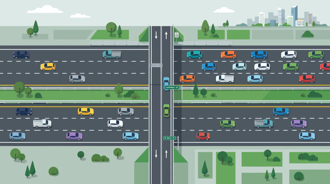 Aerial view of a busy highway intersection with a city skyline in the background