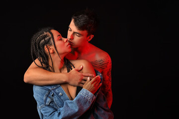 Fototapeta premium Young couple kissing on black background