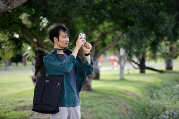Fototapeta premium Young Asian Travel Photographer Taking Pictures in Green Park