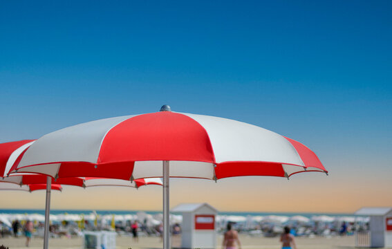 Geometric umbrellas create cool oases of shade on the hot sand by the crystal-clear sea.