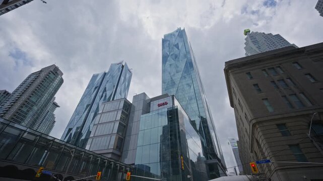 Low angle pan of CIBC SQUARE North and South towers with modern glass facade and striking architectural design in downtown Toronto's financial district on overcast day