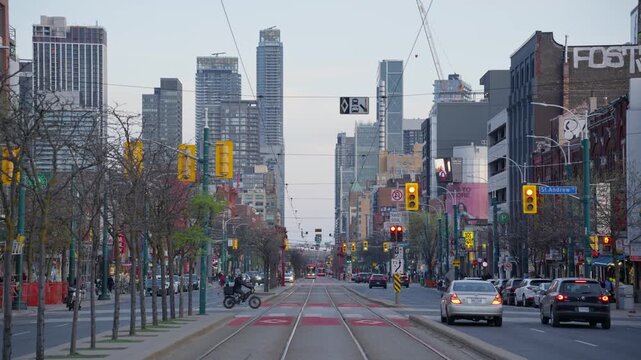 Busy avenue in Toronto downtown with city traffic, modern skyscrapers, public transportation tramways during typical urban day in North American metropolis