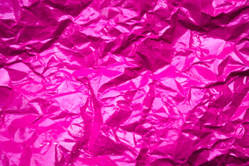 Fototapeta premium Crumpled Metallic Foil Background in Vibrant Magenta Pink with Shiny Glare, Textured Creased Aluminum Foil Wrap Sheet Texture for Abstract Festive Designs, Celebration Backdrop, and Modern Patterns