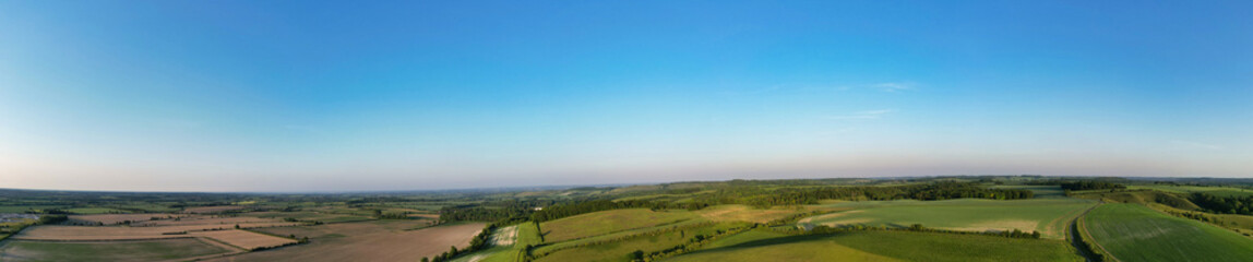 Obraz premium High Angle View of British Countryside and Landscape of Bedfordshire England UK. Drone Camera Footage Was Captured Medium High Altitude During Bright Sunny Day With Blue Sky and Hot Summer Day