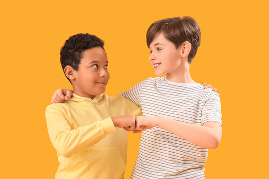 Little boys bumping fists on yellow background. Children's Day celebration