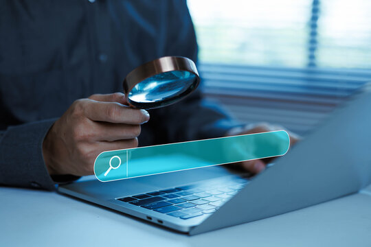 Business professional using magnifying glass and digital search bar on laptop, concept of online search, information discovery, data research, web browsing, SEO analysis, investigation,
