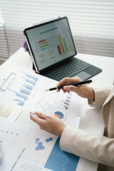 Business professional reviewing financial reports and performance charts at a modern office desk, analyzing data, planning strategy, and managing corporate documentation. © Witoon