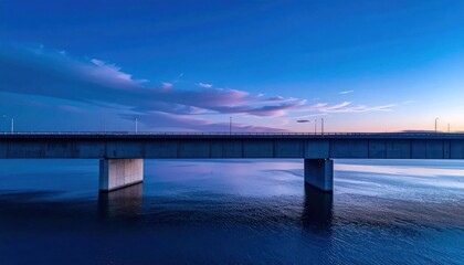 Obraz premium Modern concrete bridge at twilight under a vast blue and purple sky reflecting on calm water serene minimalist landscape