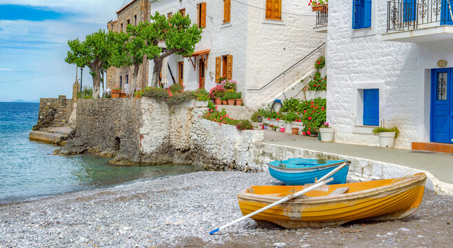 white house with colorful shutters of a seaside village with boats on the beach in Peloponnese Greece