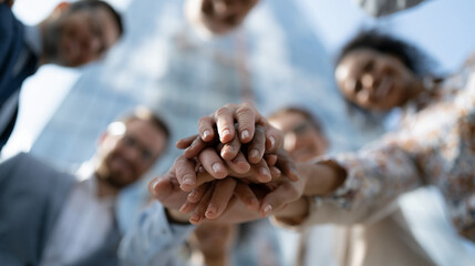 Obraz premium Unity Hands Stacked: A diverse group of business colleagues forming a huddle with their hands stacked in the center, symbolizing trust, teamwork, and shared purpose.