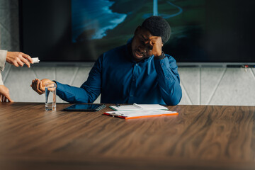 Fototapeta premium Stressed businessman taking medicine for a headache