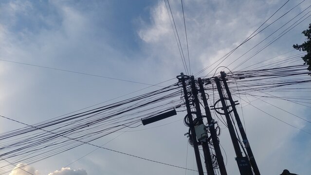 Overhead power lines against a backdrop of a vibrant blue sky with scattered clouds