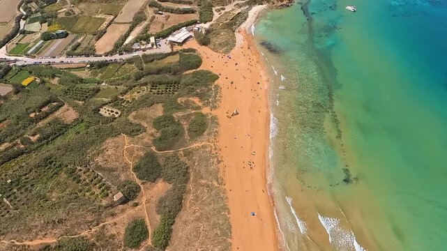 Aerial video of Ramla beach in Gozo from a drone flying backwards, revealing slowly the landscape of the island
