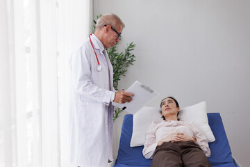 Obraz premium Senior doctor providing medical care and consultation, discussing diagnosis with a young female patient lying on a clinic bed, focusing on healthcare and wellness