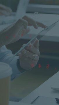 Vertical video: Man using tablet tapping making red HUDs on screen as peer typing syncing business