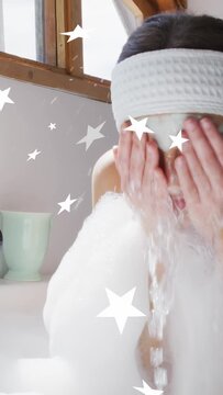 Vertical video: Woman scooping foam, rinsing and patting face in skincare bath, stars floating